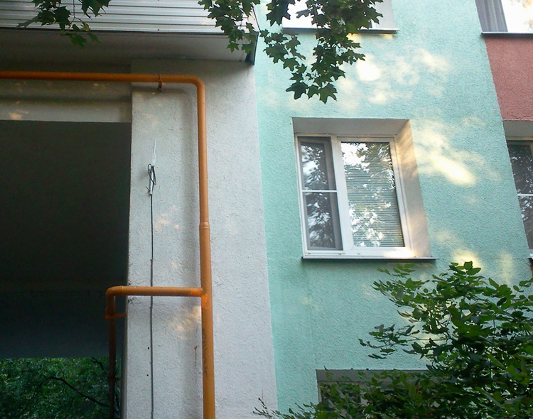 антенна на стене дома около окна над козырьком подъезда жилого дома